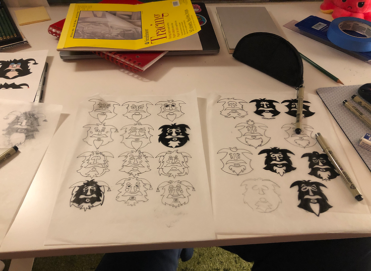 A messy desk with sketches of previous kuker logo iterations.